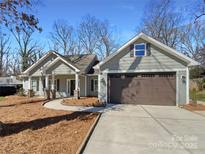 Charming single-story home with gray siding, inviting front porch, and a convenient two-car garage at 5219 Hoover Dr, Charlotte, NC 28269