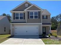Charming two-story home boasts neutral siding, a two-car garage, and a well-manicured lawn on a sunny day at 668 Lamorak Pl, Richburg, SC 29729