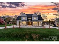 Stunning two-story home boasting a spacious front yard, covered porch, and complemented by a vibrant sunset at 400 Canvasback Rd, Mooresville, NC 28117