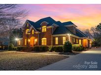 Stunning two-story brick home featuring manicured landscaping and a welcoming entrance during a colorful sunset at 4421 Windwood Cir, Charlotte, NC 28226