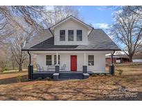 Charming two-story home boasts a welcoming front porch, fresh white paint, and a striking red front door at 201 Pleasant Ave, Stanfield, NC 28163