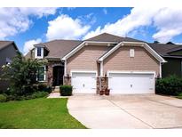 Charming home featuring a two-car garage, stone accents, shake siding, and manicured lawn with lush greenery at 246 Sweet Briar Dr, Fort Mill, SC 29707