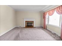 Inviting living room featuring a cozy fireplace, large window, and neutral carpet at 2922 Dunlavin Way, Charlotte, NC 28205