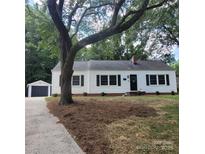 Charming single-story home with black shutters and a detached garage, nestled under mature trees at 1003 Woodland Dr, Gastonia, NC 28054