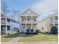 Charming two-story home features a double porch, a blue front door, and well-maintained landscaping at 12304 Huntersville Concord Rd, Huntersville, NC 28078