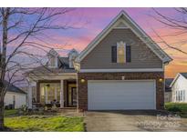 Charming home featuring a brick facade, two-car garage, well-manicured lawn, and covered front porch at sunset at 14014 Acorn Creek Ln, Charlotte, NC 28269