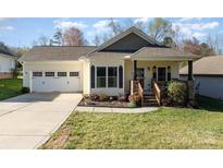 Charming single-story home featuring a well-manicured lawn, inviting front porch, and an attached two-car garage at 215 Maple St, Locust, NC 28097