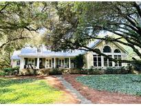 Charming home with a inviting front porch, lush landscaping, and mature trees, providing shade and beauty at 7794 Live Oaks Dr, Denver, NC 28037