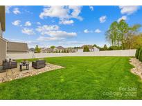 Expansive backyard with lush green grass, complemented by a patio seating area and a white fence at 963 Brookdale Ln, Stanley, NC 28164