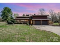 A brick home with a large front yard and an attached three car garage under a pink and purple sky at 190 Country Dr, Statesville, NC 28625