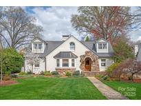 Charming white home with stone accents, a manicured lawn, and mature trees on a beautifully landscaped lot at 2237 Colony Rd, Charlotte, NC 28209