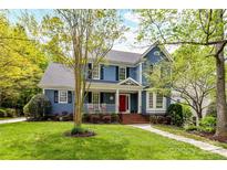 Charming two-story home with a welcoming front porch, red door, and well-manicured lawn at 306 Ashby Dr, Davidson, NC 28036