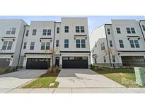 New construction townhome featuring a two-car garage, neutral landscaping, and modern curb appeal at 9239 Delancey Nw Ln, Concord, NC 28027