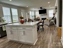Open-concept kitchen features a large island with white cabinets and stainless steel hardware, seamlessly connecting to the dining and living areas at 1308 Old Concord Rd, Salisbury, NC 28146