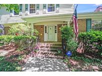 Inviting brick home entrance with American flag, landscaped shrubs and front steps at 1327 Cedarwood Ln, Charlotte, NC 28212