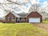 Charming brick home with an attached two-car garage, mature trees, and a well-maintained lawn at 1520 Venture Oaks Ln, Monroe, NC 28110
