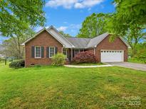 Charming brick home with a well-manicured lawn and attached two-car garage on a sunny day at 1520 Venture Oaks Ln, Monroe, NC 28110