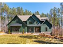 Stunning two-story home featuring green siding, a stone foundation, and beautifully landscaped front yard at 157 Silver Falls Dr, Troutman, NC 28166