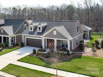 Charming single-story home featuring a two-car garage, dormer windows, and inviting front porch with a landscaped garden at 2011 Trailwood Dr, Matthews, NC 28104