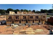New townhomes in progress showing the framing and foundations of the two-story buildings, with lumber on the ground at 3003 Casting St # 12, Charlotte, NC 28206