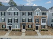A detailed view of the townhome exteriors featuring stone accents, neutral paint, and black window shutters at 3104 Timber Mill Dr, Matthews, NC 28104