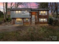 Charming split-level home featuring a brick facade, gray siding, and a well-manicured lawn at 326 Whispering Pines Dr, Charlotte, NC 28217