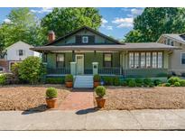 Charming green bungalow with a covered front porch, brick walkway, and lush landscaping at 36 Yorktown Nw St, Concord, NC 28025