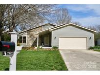 Charming home featuring a stone accent wall, light gray siding, and a well-manicured front lawn at 7529 Sheffingdell Dr, Charlotte, NC 28226