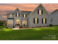 Charming two-story home with white brick, black shutters, and a well-manicured front lawn at 873 Penny Royal Ave, Fort Mill, SC 29715