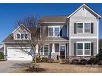 Charming two-story home with gray siding, stone accents, manicured landscaping, and inviting front porch at 1022 Doughton Ln, Indian Trail, NC 28079