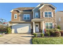 Inviting two-story home with a two-car garage, beautiful stone accents, and a well-manicured lawn at 10321 Solar Way, Charlotte, NC 28278