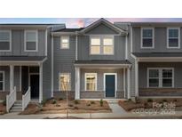 Beautiful gray two-story townhome featuring a covered front porch, professionally landscaped yard and stylish design at 104 Ciara Pl # B, Mooresville, NC 28117