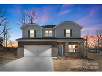 Charming two-story home with a brick and siding exterior, a two-car garage, and a well-maintained lawn at 117 Obadiah Ct, Troutman, NC 28115