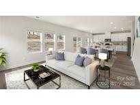 Bright living room featuring a plush white sofa, stylish décor, and an open floor plan leading into the kitchen at 117 Obadiah Ct, Troutman, NC 28115