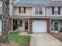 Charming two-story townhome featuring a one-car garage and well-maintained front lawn and brick accents at 11911 Maria Ester Ct, Charlotte, NC 28277