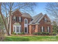 Charming red brick home with a manicured lawn, mature trees, and inviting entrance at 13604 Edgetree Dr, Pineville, NC 28134