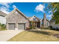 Charming stone-accented home with a manicured lawn and two-car garage under a beautiful blue sky at 14920 High Bluff Ct, Charlotte, NC 28278