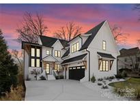 Stunning two-story home featuring white brick, black trim, a dark garage door, and a concrete driveway at 680 Ideal Way, Charlotte, NC 28203