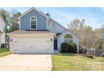 Charming two-story home featuring a two-car garage, blue accents, and well-maintained landscaping at 7343 Rock Island Rd, Charlotte, NC 28278