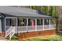 Charming home featuring a covered front porch with an American flag and rocking chairs at 9401 Elvis Dr, Charlotte, NC 28215