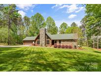 Charming stone and wood home with a stone chimney, green roof, and lush lawn at 123 Lucy Ln, Statesville, NC 28625