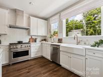 Bright kitchen featuring stainless steel appliances, a farmhouse sink, and beautiful dark hardwood floors at 317 Old Town Village Rd, Waxhaw, NC 28173
