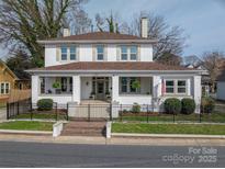 Charming two-story home featuring a covered front porch, manicured landscaping, and a wrought-iron fence at 615 E Sycamore St, Lincolnton, NC 28092