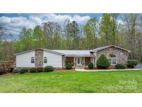 Charming ranch home featuring stone accents, a metal roof, and a well-manicured lawn and landscaping at 1514 Ring Tail Rd, Claremont, NC 28610