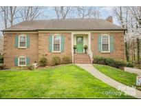 Charming brick home featuring a manicured lawn, green shutters, and a welcoming front entrance at 15920 Fieldstone Dr, Matthews, NC 28104
