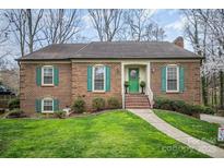 Charming brick home features a well-manicured lawn and vibrant green shutters, offering classic curb appeal at 15920 Fieldstone Dr, Matthews, NC 28104