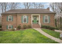 Charming brick home featuring green shutters, a welcoming front door, and a well-manicured lawn at 15920 Fieldstone Dr, Matthews, NC 28104