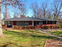 Charming red brick home featuring a well-maintained lawn and mature trees against a clear blue sky at 207 Oak Dr, Belmont, NC 28012