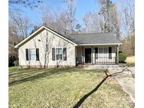 Charming one-story home with a well-maintained lawn, black shutters, and a cozy front porch at 218 Cottonwood Park Dr, Charlotte, NC 28214