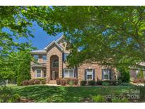 Stately brick home with manicured lawn and lush landscaping on a sunny day at 3017 Chisholm Ct, Waxhaw, NC 28173